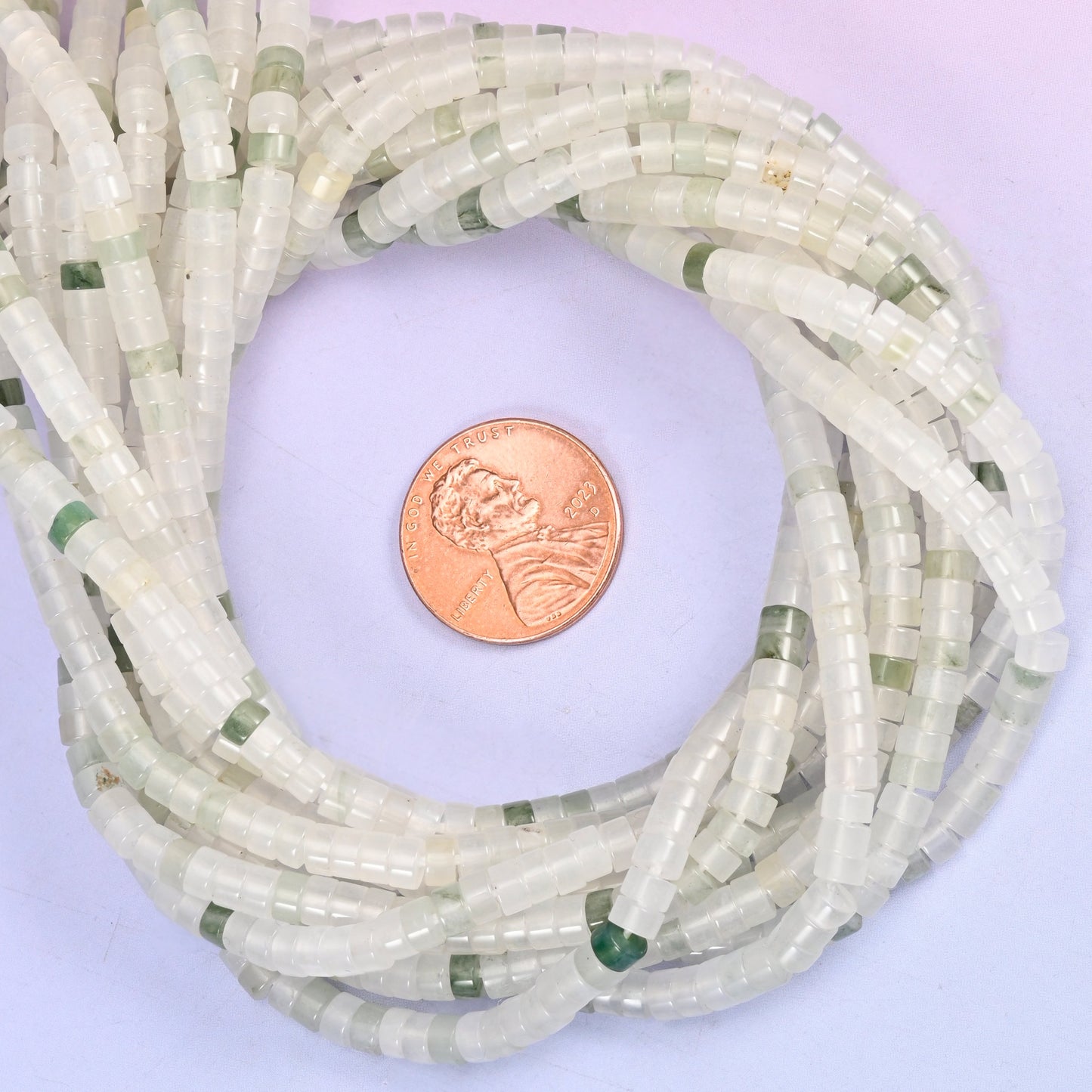 Tianshan Jade smooth heishi disc bead strands coiled around a US penny for size reference