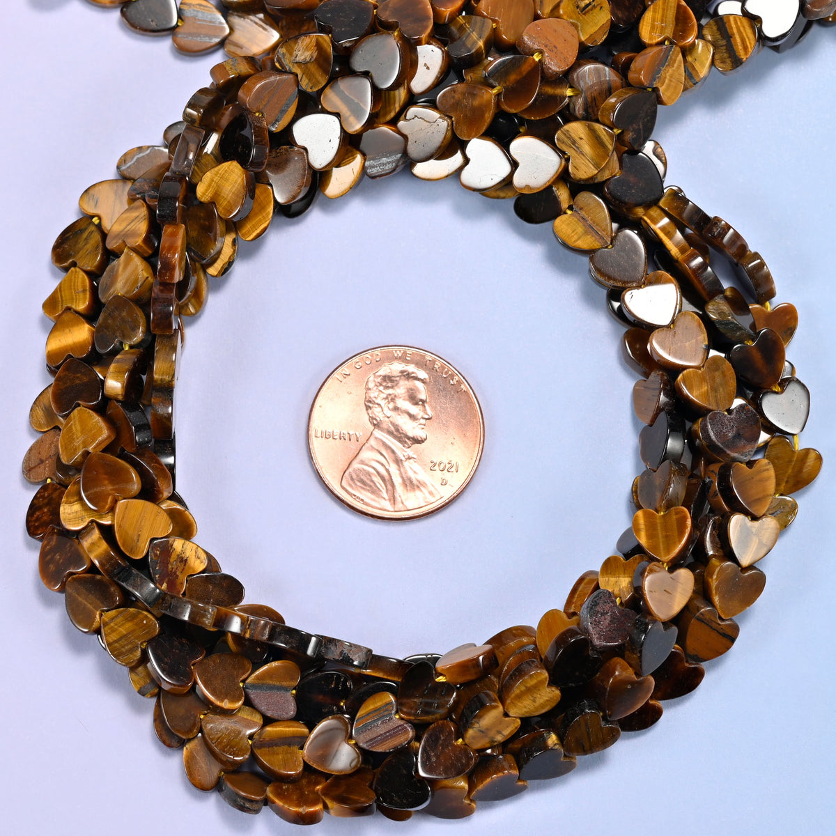 Tiger Eye flat heart bead strands coiled around a US penny for size reference