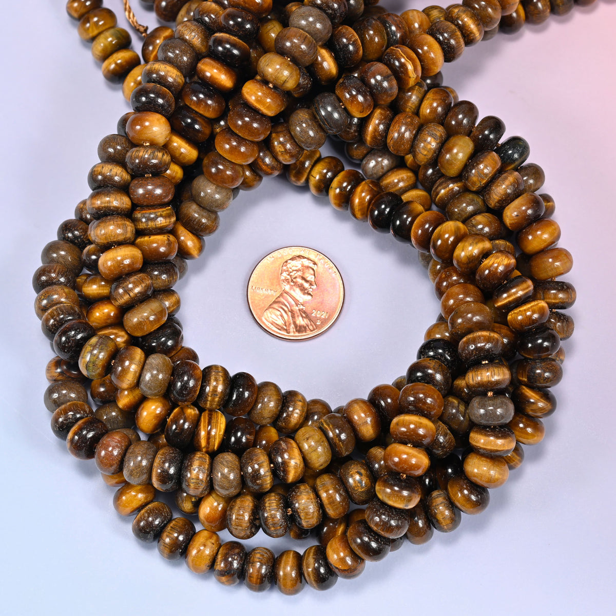 Tiger Eye rondelle bead strands coiled around a US penny for size reference