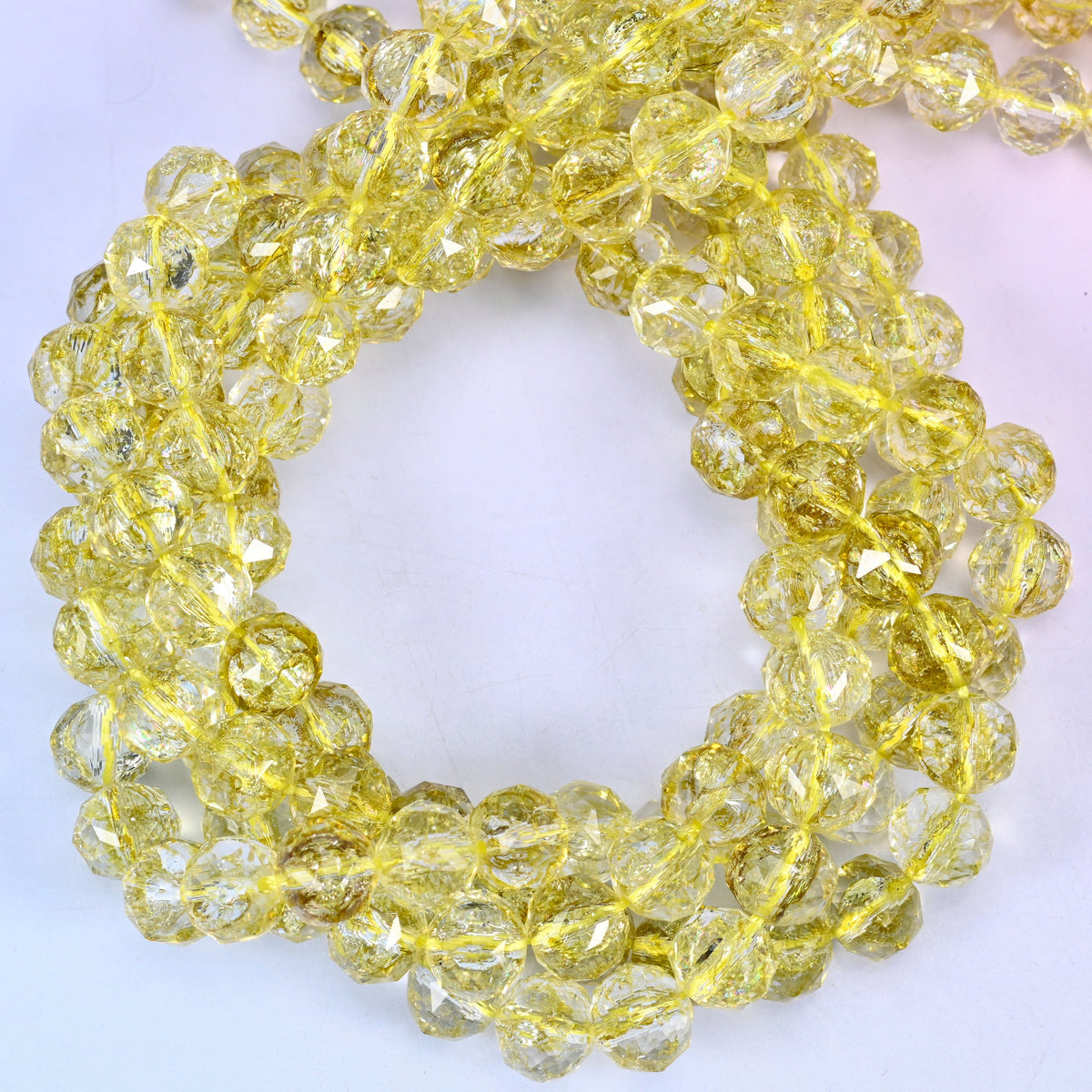 Transparent lemon yellow faceted round glass beads, close view of the coiled strands showing clear lemon yellow