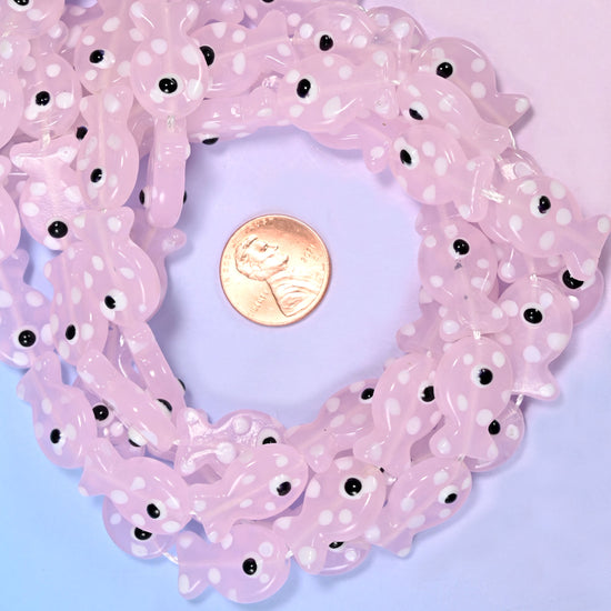 Transparent Pink with White Dot Fish glass bead strands coiled around a US penny for size reference