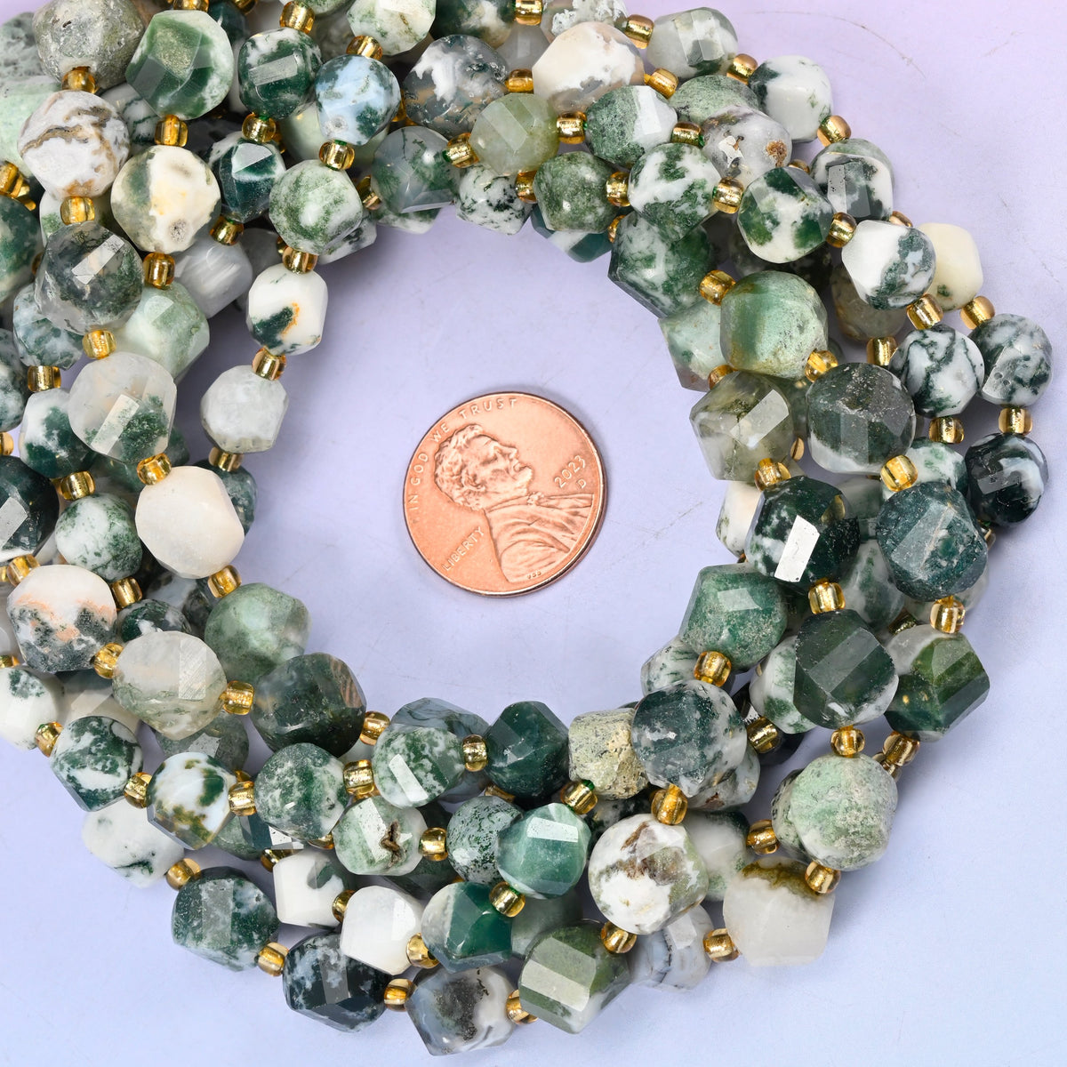 Tree Agate faceted spiral twist bead strands coiled around a US penny for size reference