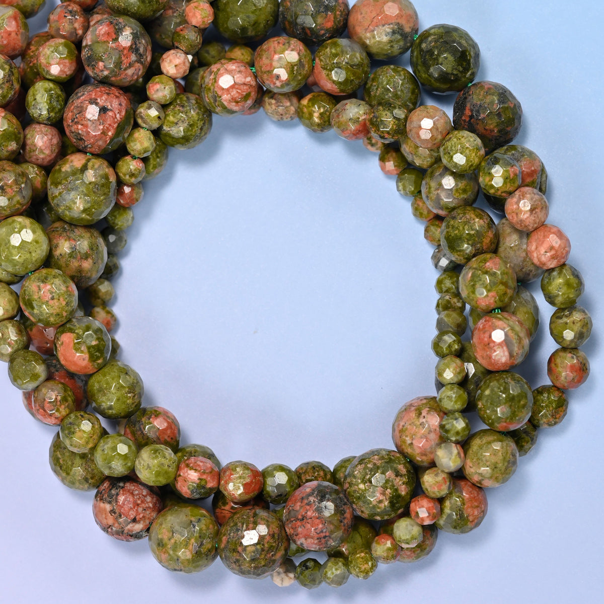 Unakite faceted round beads, close view of the coiled strands mixing olive green and salmon pink