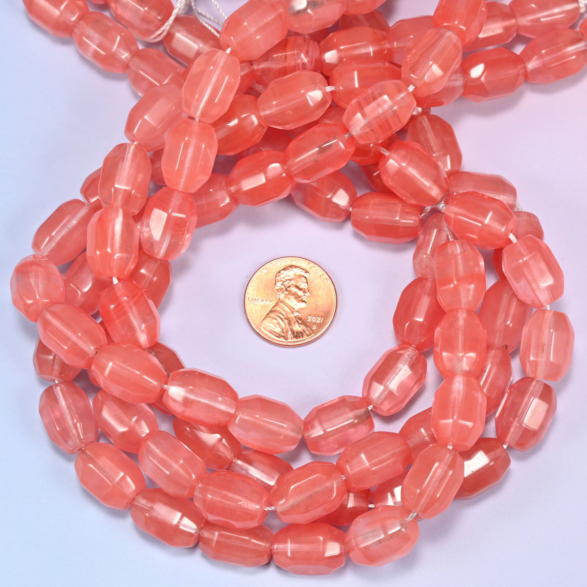 Watermelon Quartz glass faceted barrel bead strands coiled around a US penny for size reference