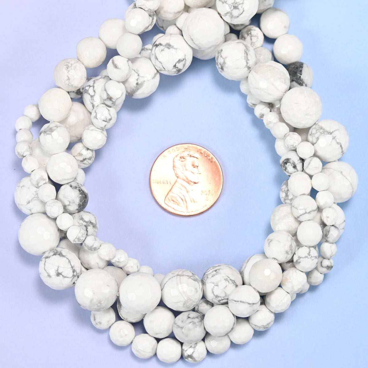 White Howlite faceted round bead strands coiled around a US penny for size reference