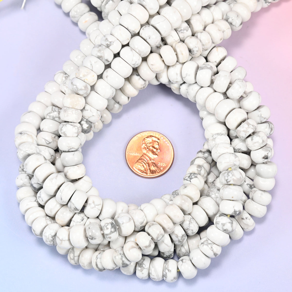 White Howlite rondelle bead strands coiled around a US penny for size reference