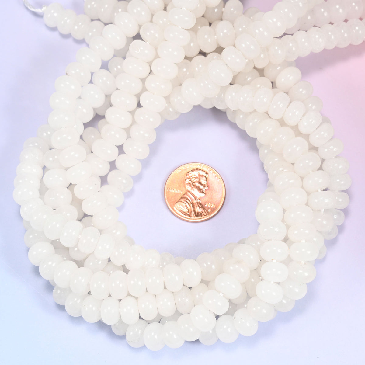 White Jade rondelle bead strands coiled around a US penny for size reference