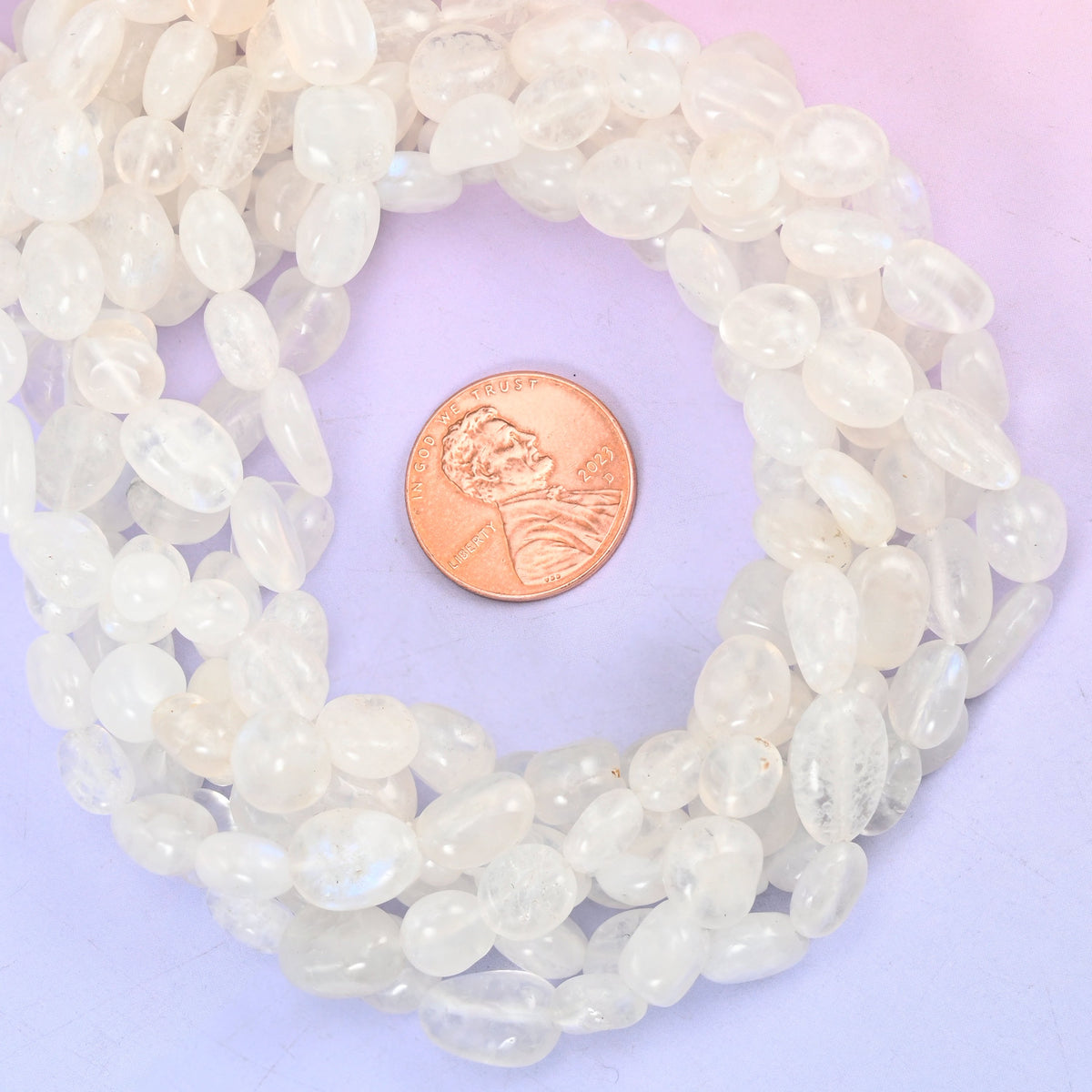 White moonstone nugget bead strands coiled around a US penny for size reference