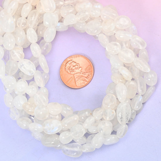 White moonstone nugget bead strands coiled around a US penny for size reference