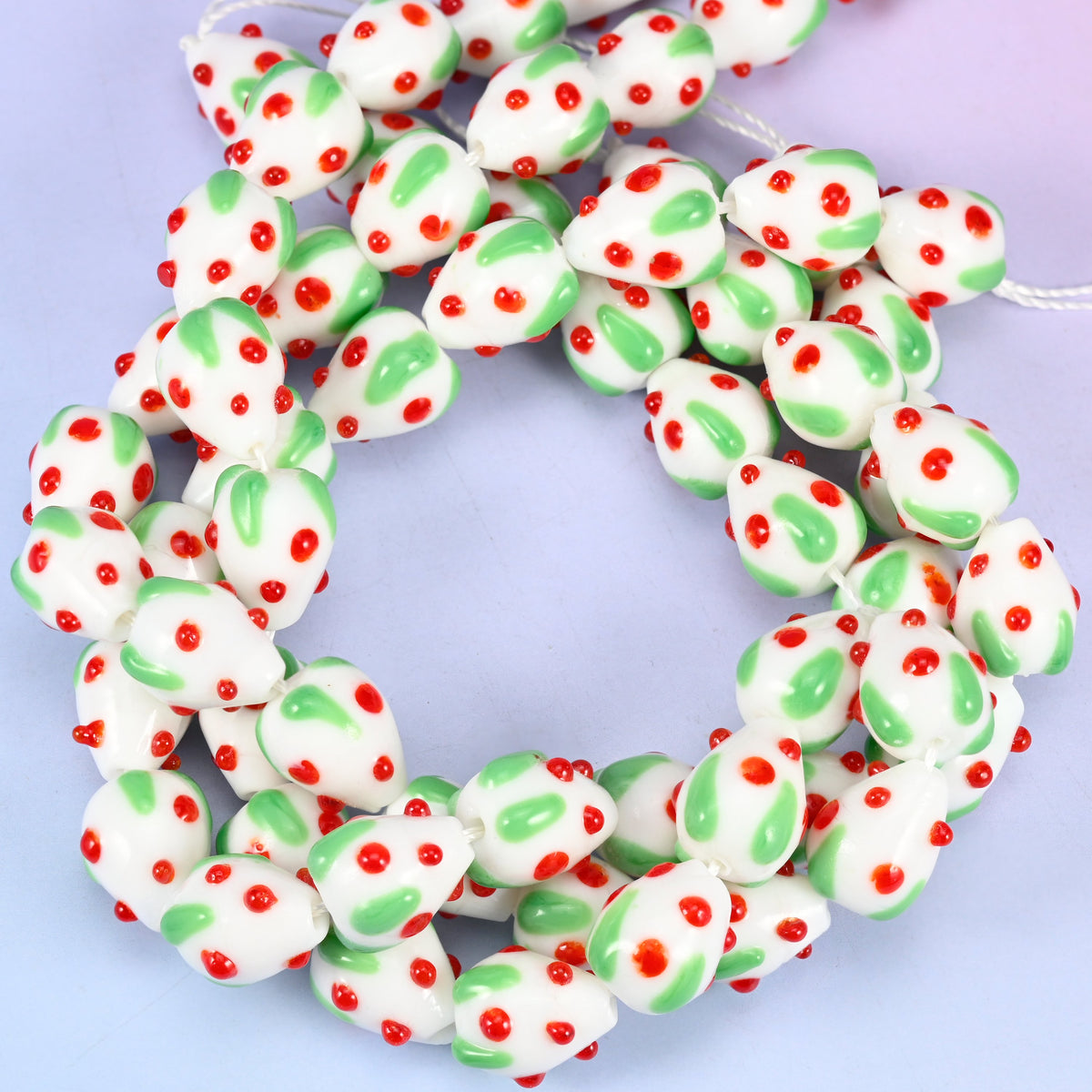 White Red Dots Strawberry glass beads, close view of the coiled strands in white with green leaves and red seed dots