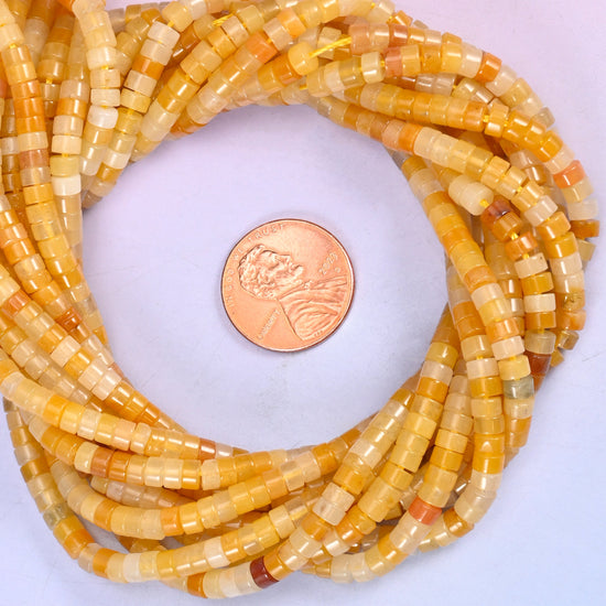 Yellow Jade smooth heishi disc bead strands coiled around a US penny for size reference