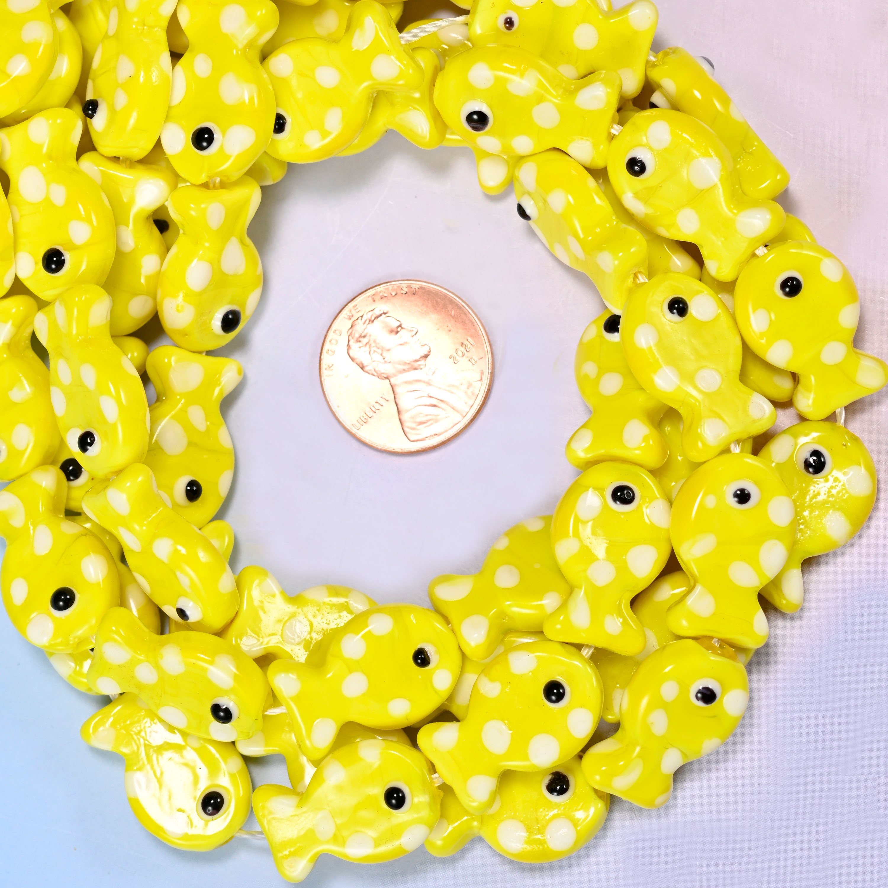 Yellow with White Dot Fish glass bead strands coiled around a US penny for size reference