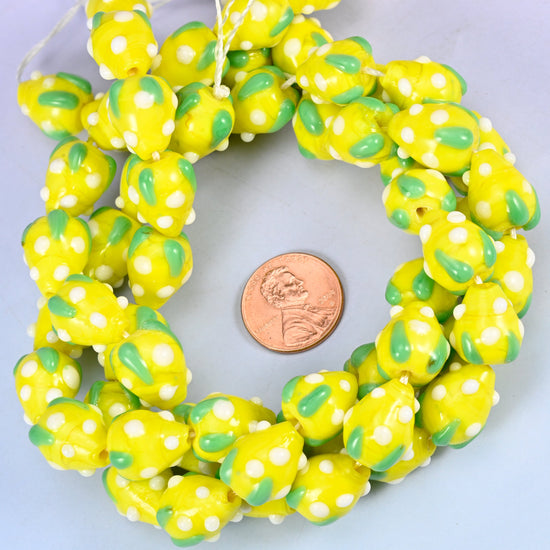 Yellow White Dots Strawberry glass bead strands coiled around a US penny for size reference