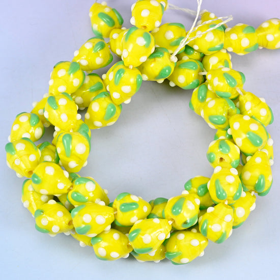 Yellow White Dots Strawberry glass beads, close view of the coiled strands in yellow with green leaf panels and white seed dots